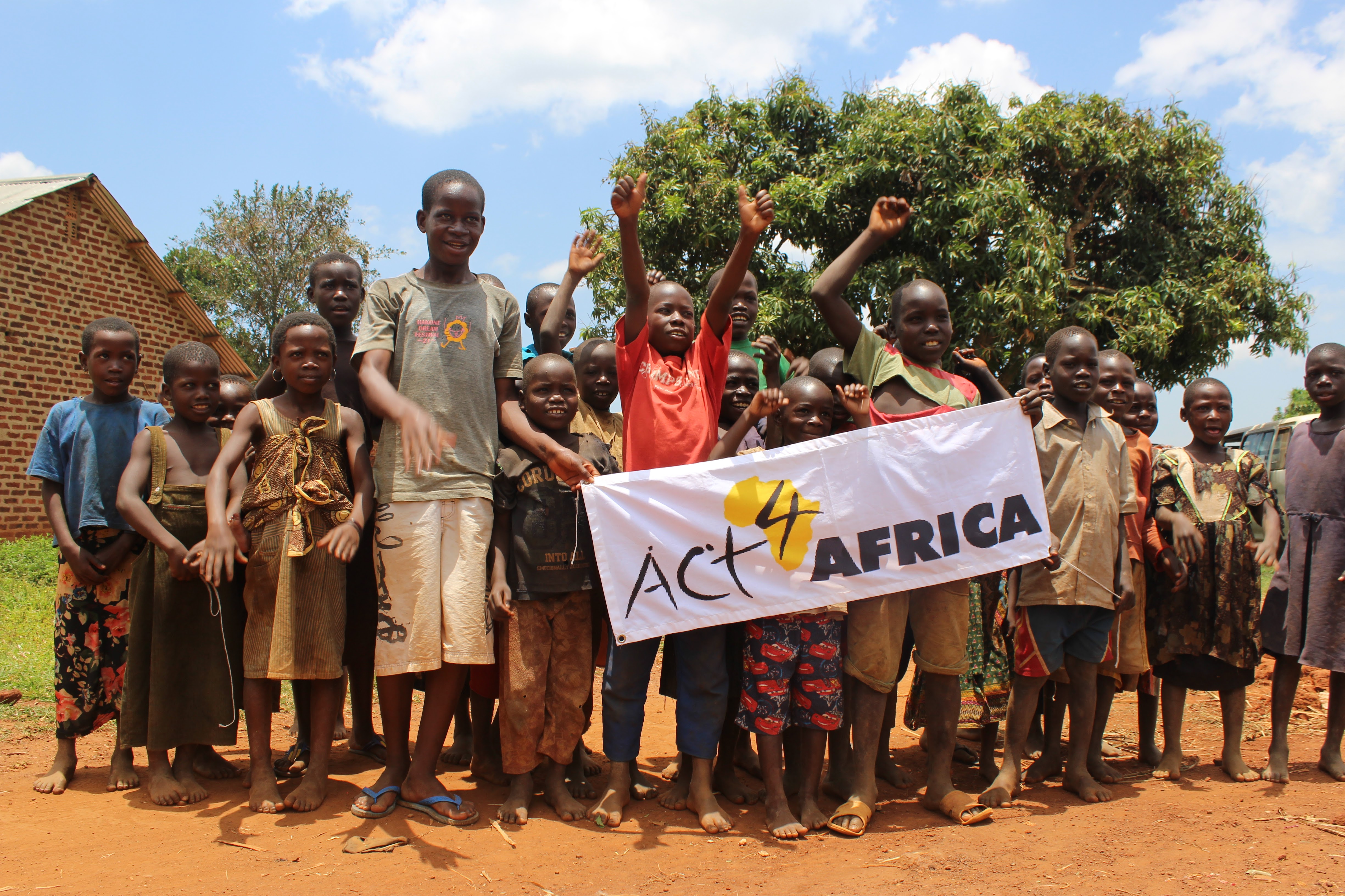 Ugandan children cheer and hold up Act4Africa banner